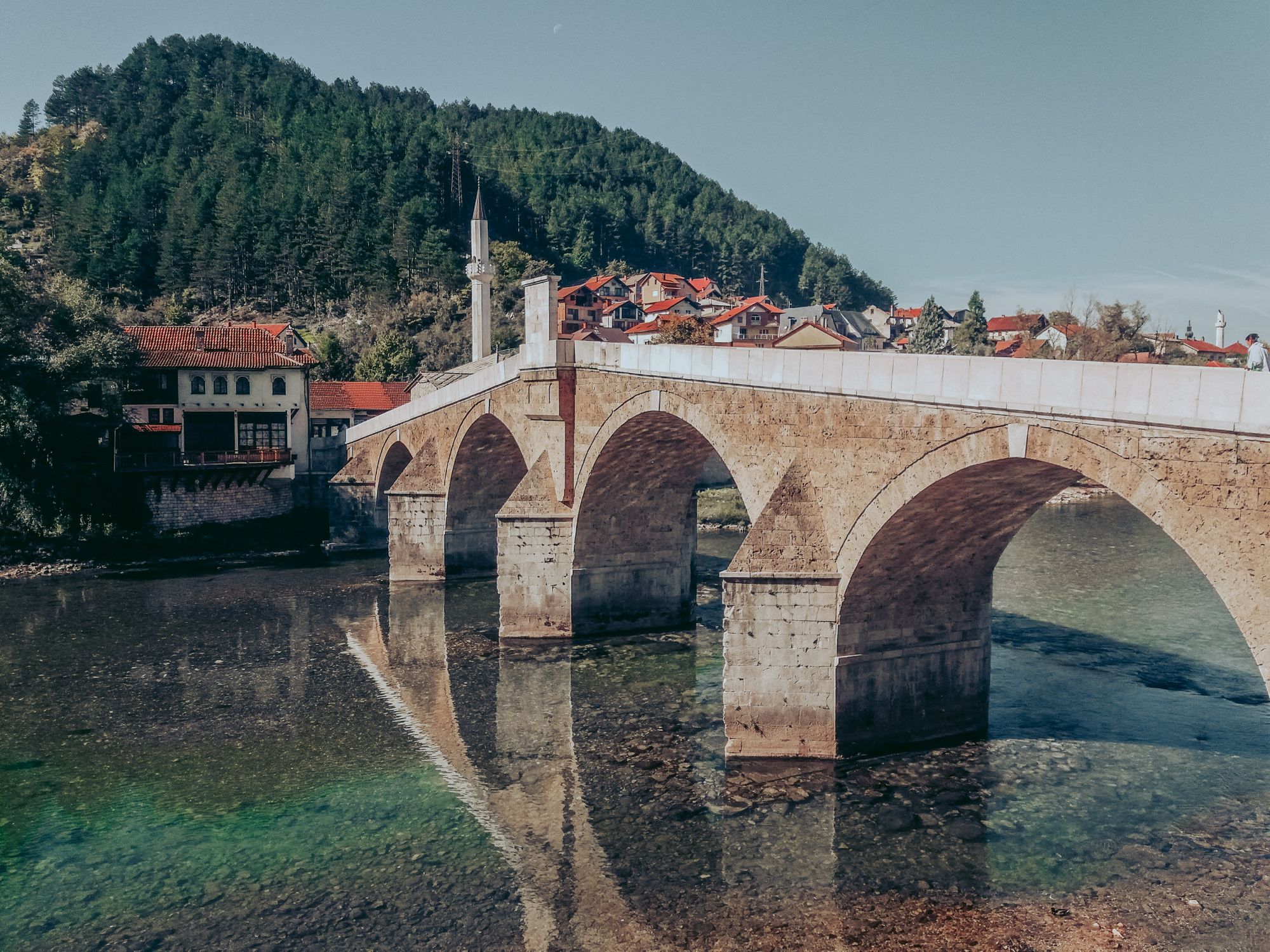 The scenic site of Konjic, Bosnia, with a bridge leading into the town.