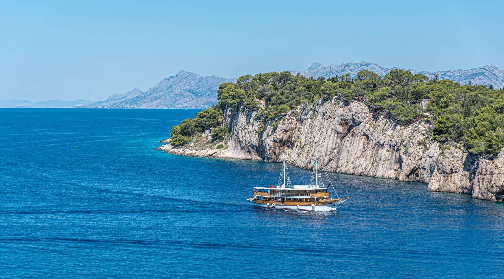A ship sails across a rocky bay of the Adriatic Sea, on the coast of Croatia