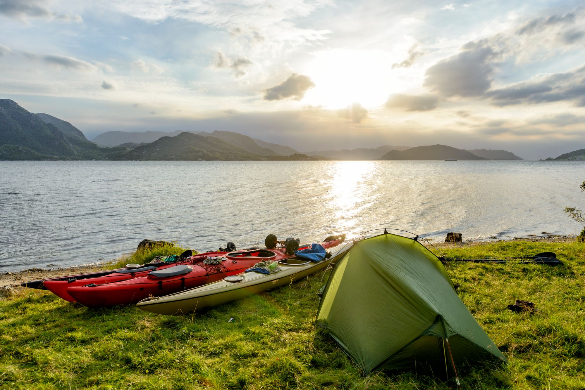 Camping beside the kayaks beside a fjord in Norway