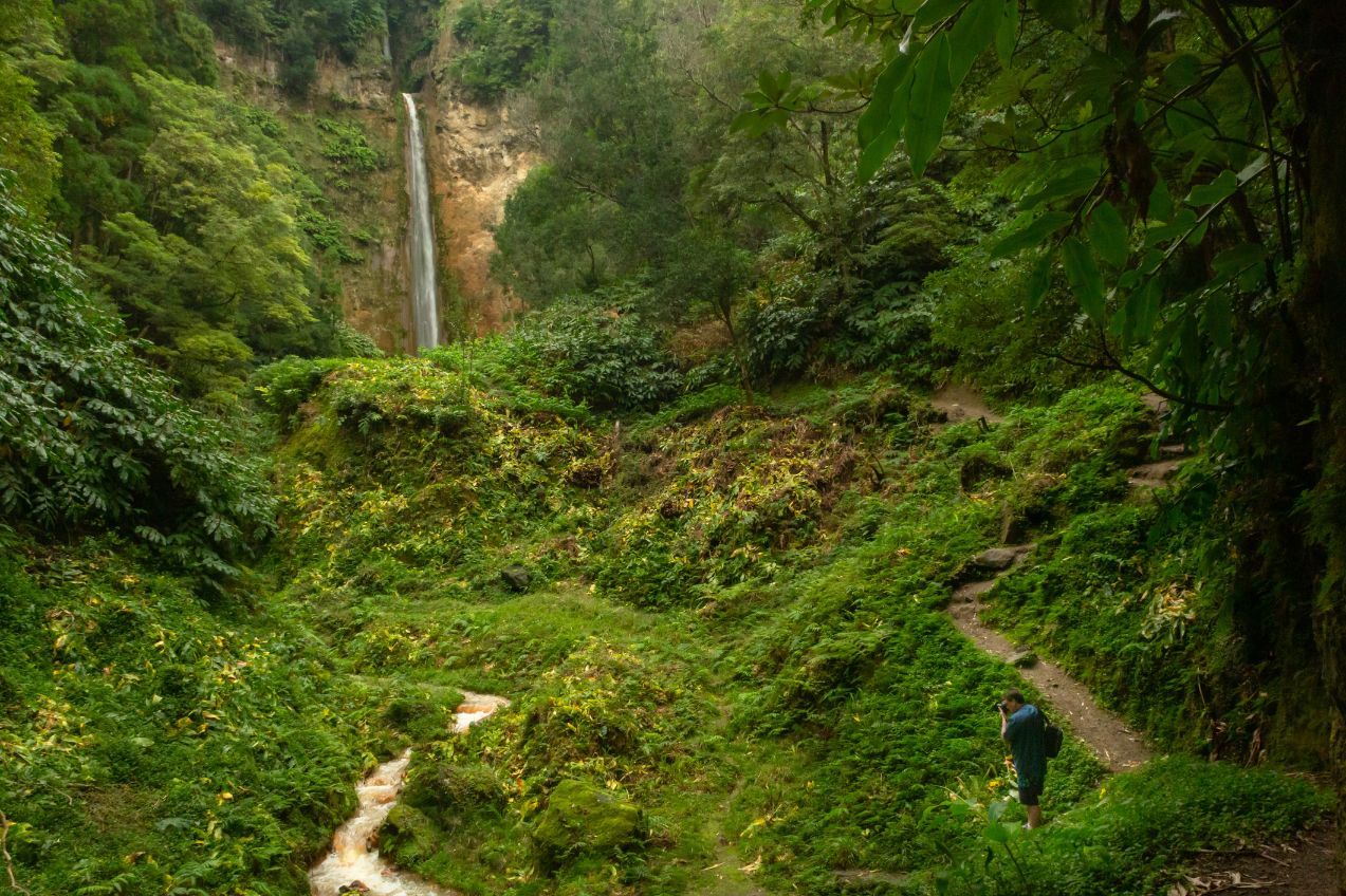 A tourist photographing the Ribeira Quente waterfall, on the Agrião Trail in the Azores. Photo: Getty