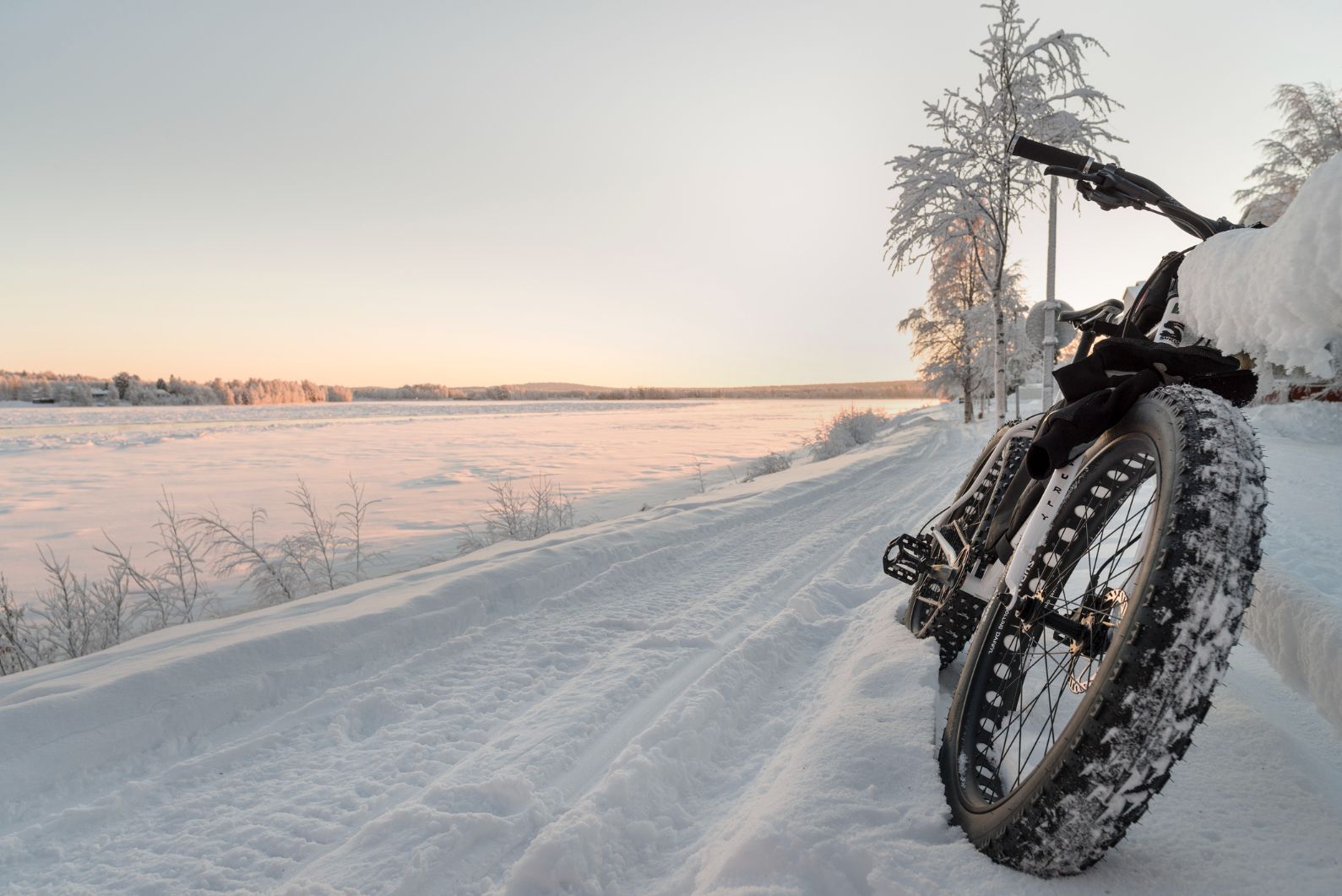 The wheels of a fat bike in the Arctic Circle, in a snowy landscape.