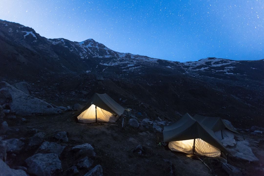 Illuminated tents at a campsite on the Deo Tibba trek, in the Indian Himalayas.