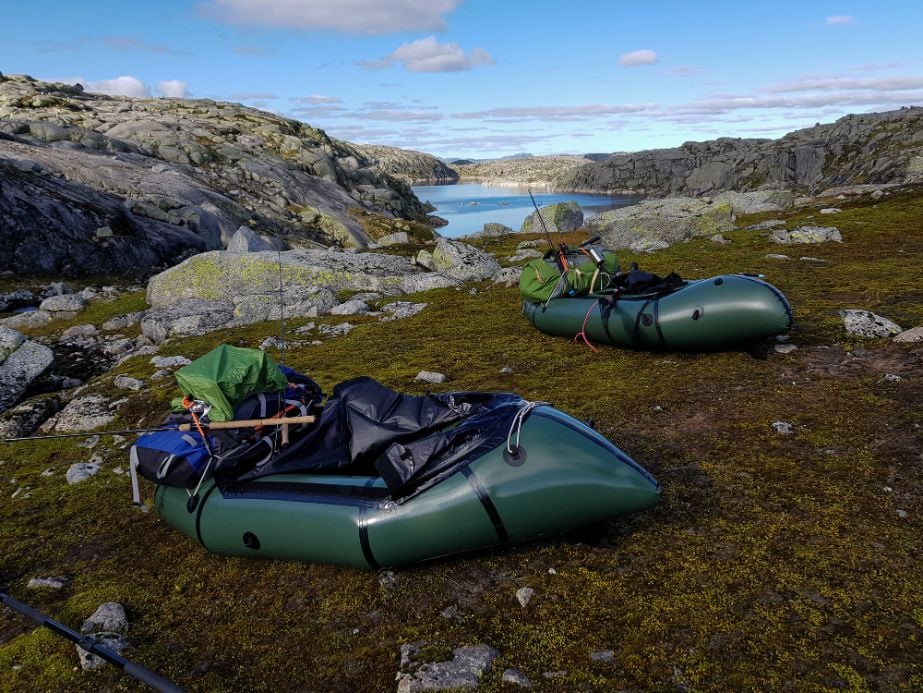 Packrafts pulled ashore - a lake surrounded by boulders in the background.