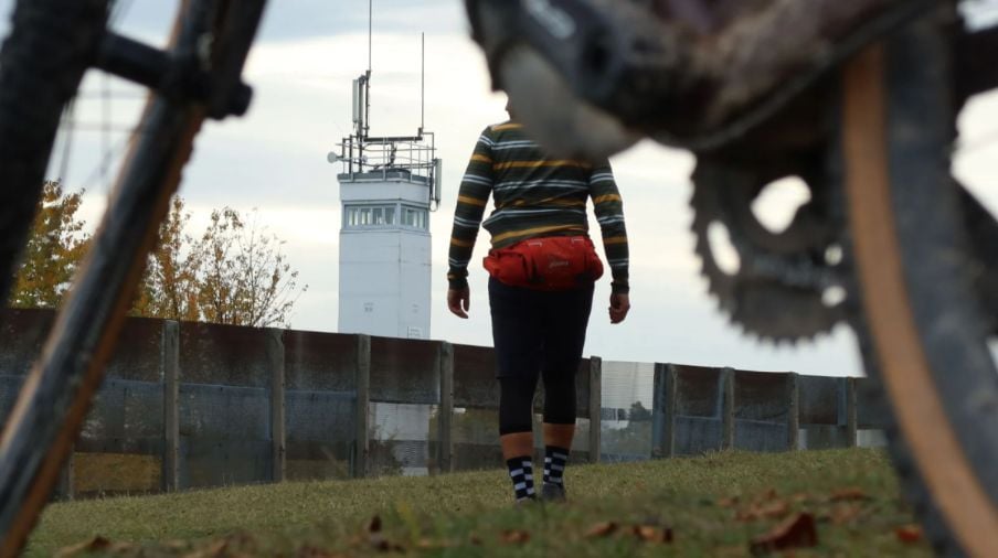 A cyclist walking towards the Iron Curtain.