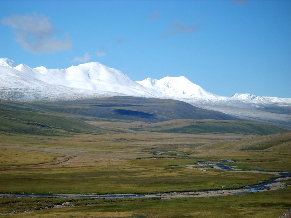 The snowy ridgeline of Khüiten Peak, the highest mountain in Mongolia, and the plains below