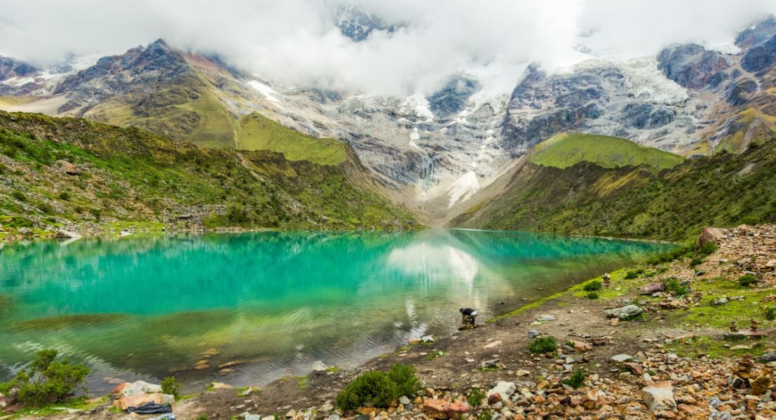 A hiker stops for a break by a mountain lake in Machu Picchu.