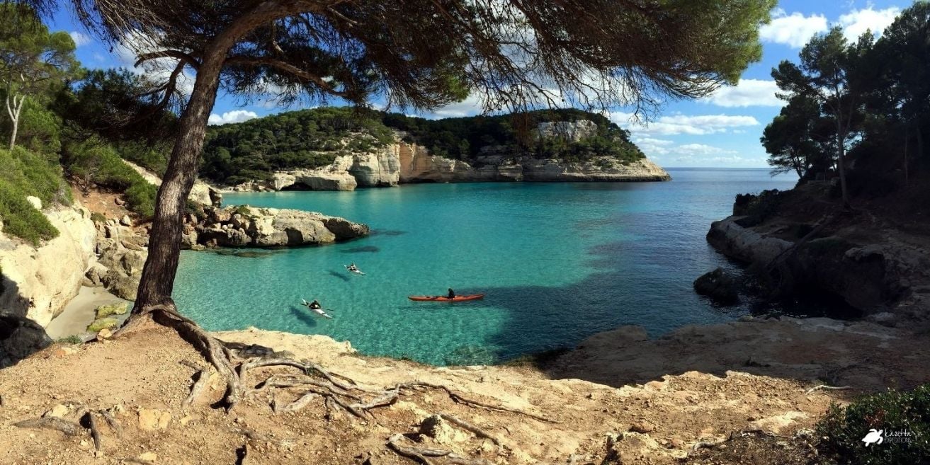 Three kayakers in a calm bay in Menorca.