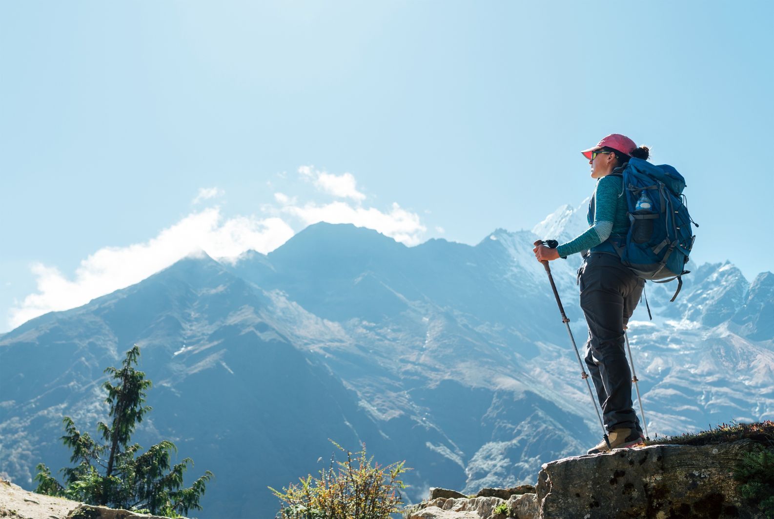 A women with trekking poles looks out over the mountainous landscape of Nepal