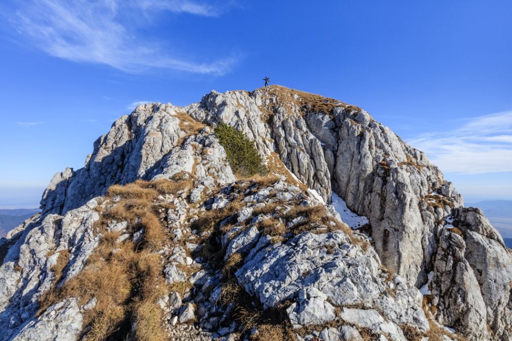 A hiker standing on the summit of one of the Piatra Craiului Mountains.