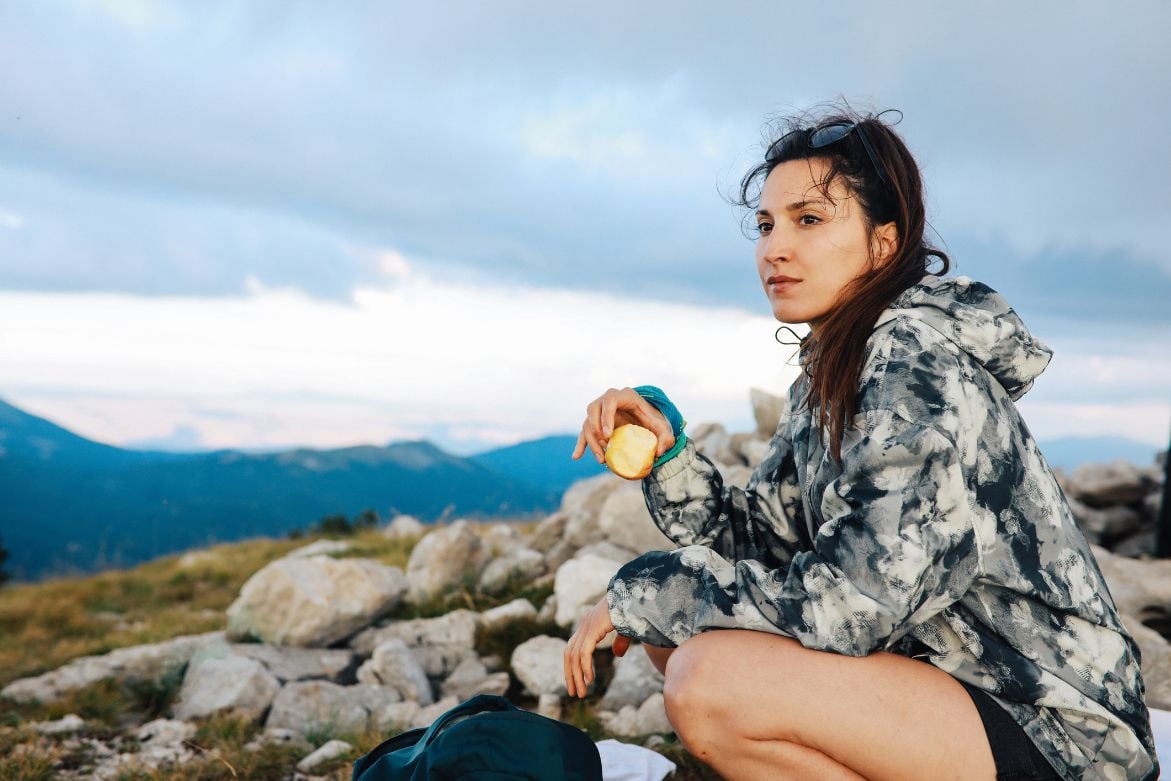 female hiker holding a half eaten apple.