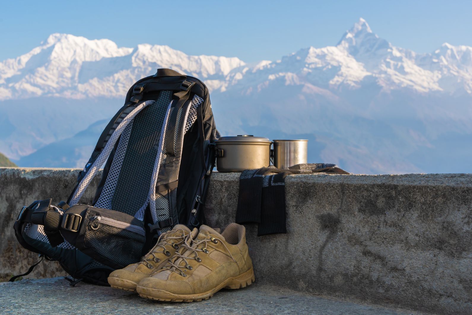 Hiking boots, a backpack and cooking equipment pictured in front of the Everest hiking region