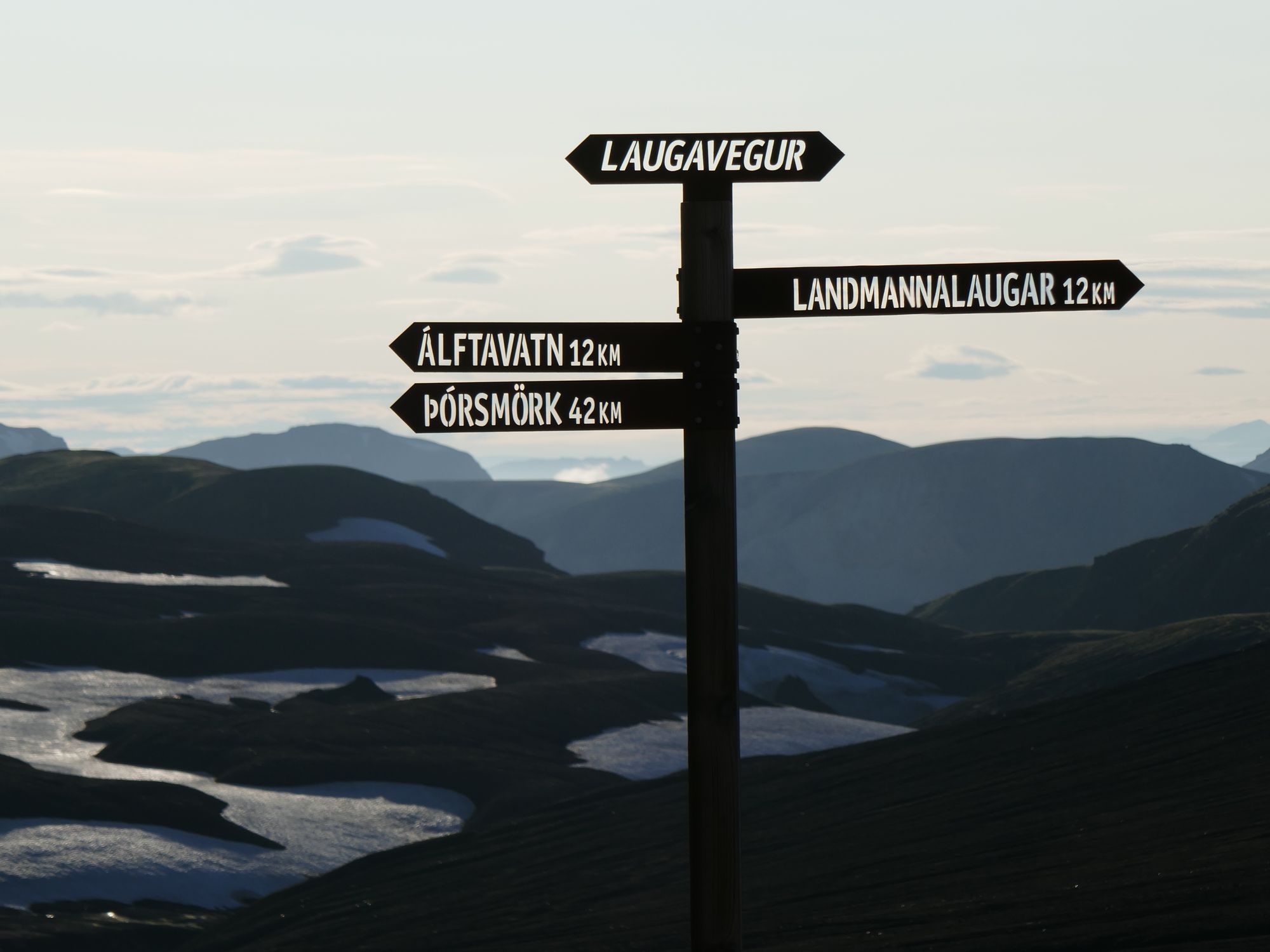 A sign in Iceland's famed Laugavegur trail, with a backdrop of snow-covered mountains behind.
