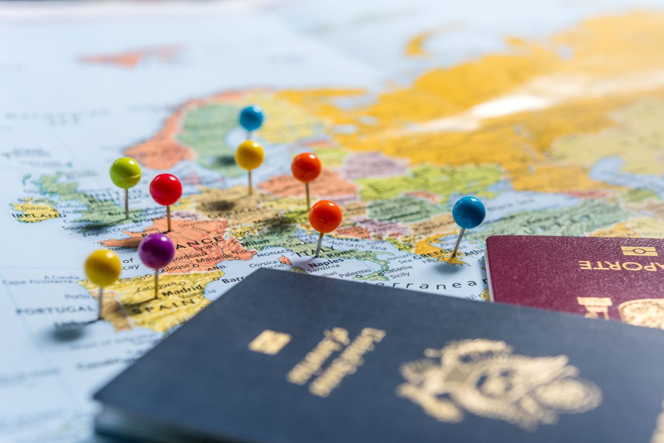 A map with pins stuck into it, and two passports on top of it.