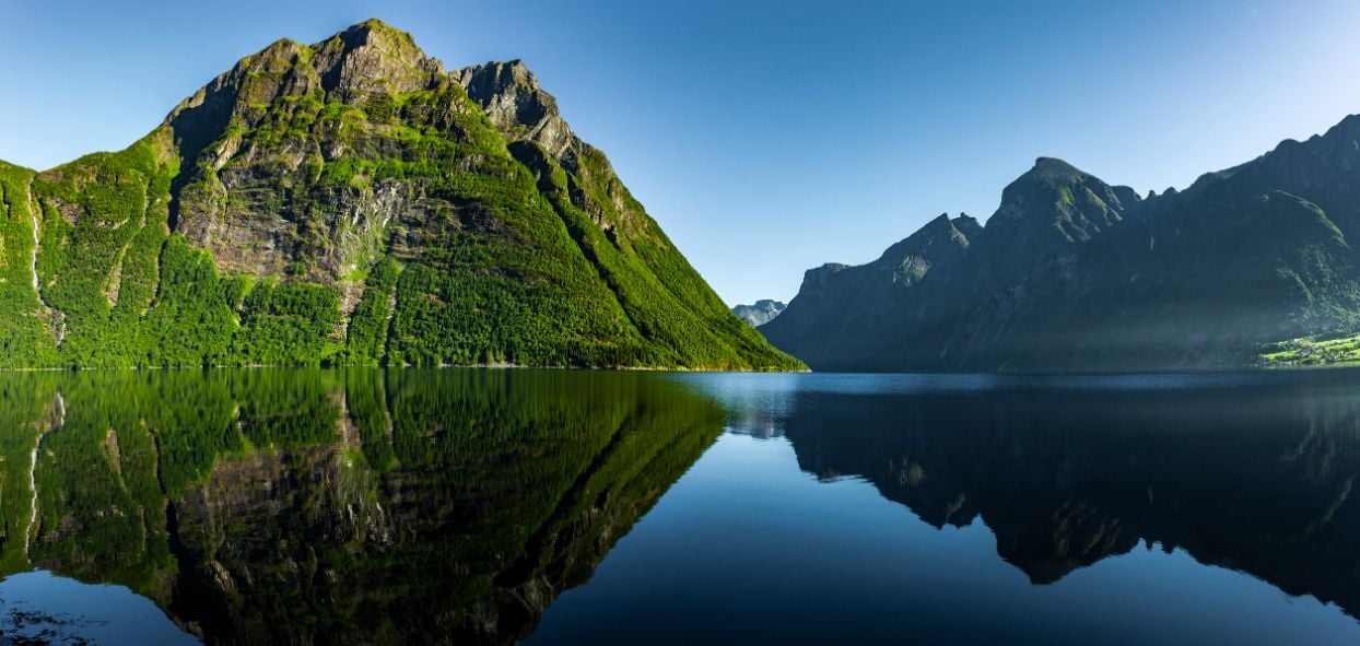 Classic mountain shapes plunging into the waters of Hjørundfjord