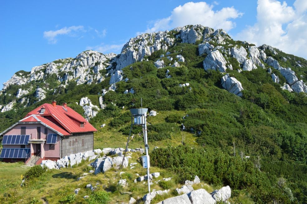 A mountain hut with a karst peak behind in Risnjak National Park, Croatia.