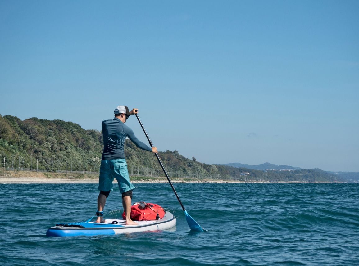 A man stand-up paddling in the ocean.