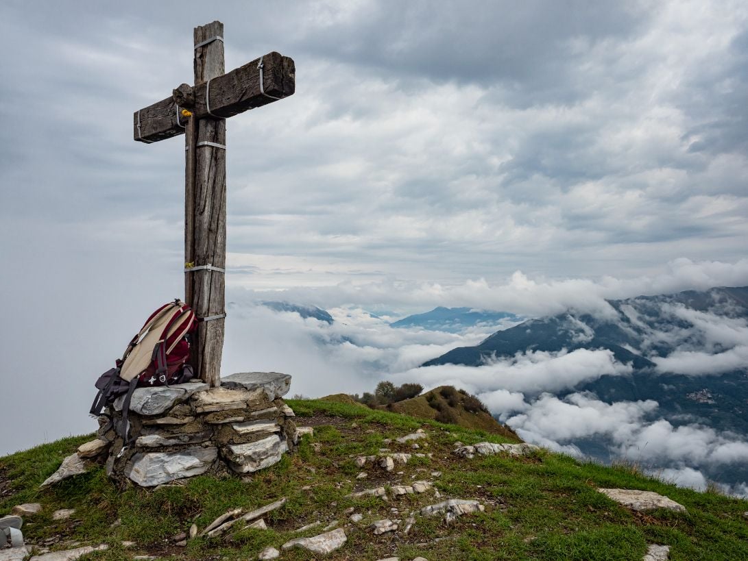 A wooden cross above Lake Como surrounded by clouds