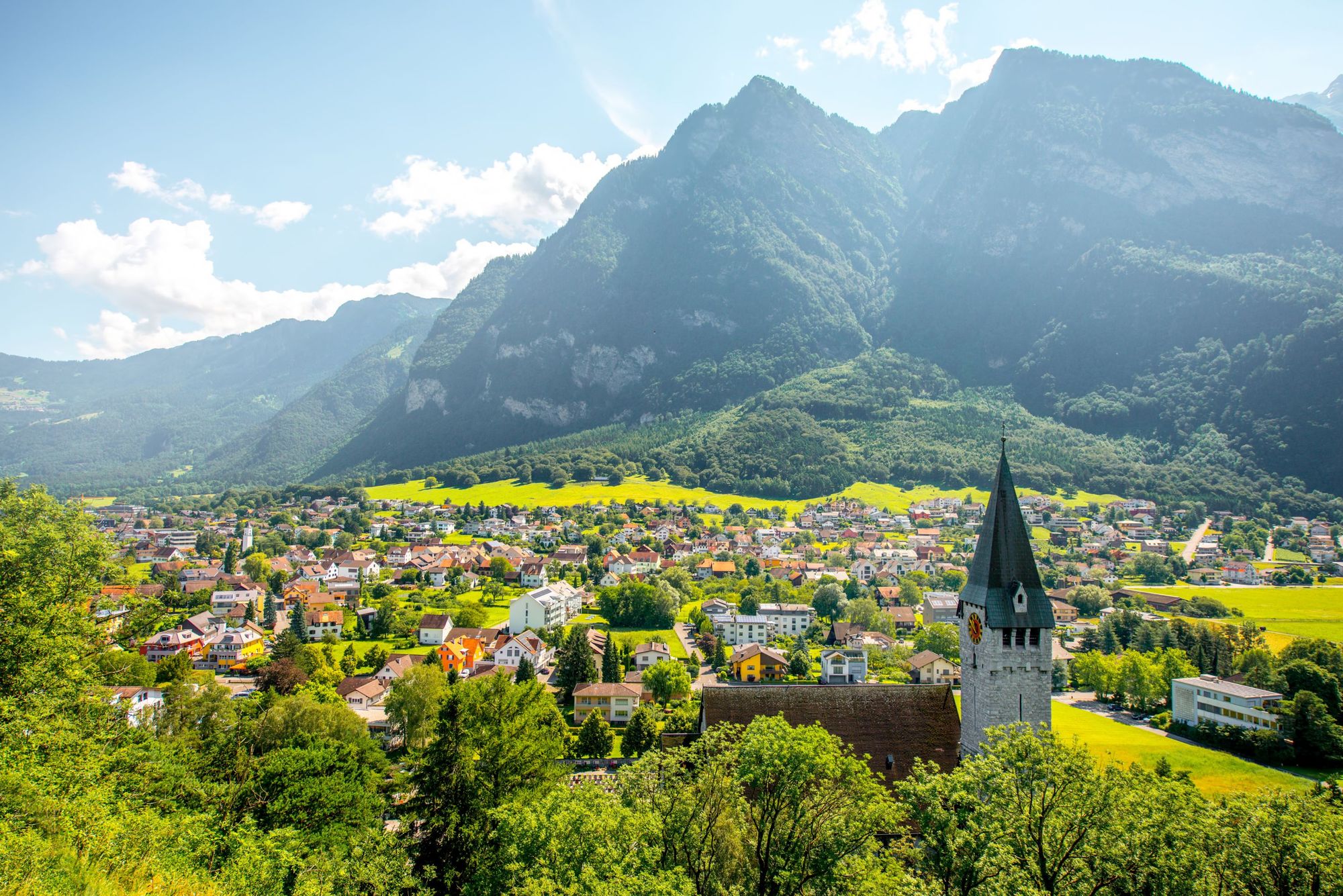 The green, vibrant view of Balzers village, with St. Nicholas church in the foreground, in Liechtenstein.