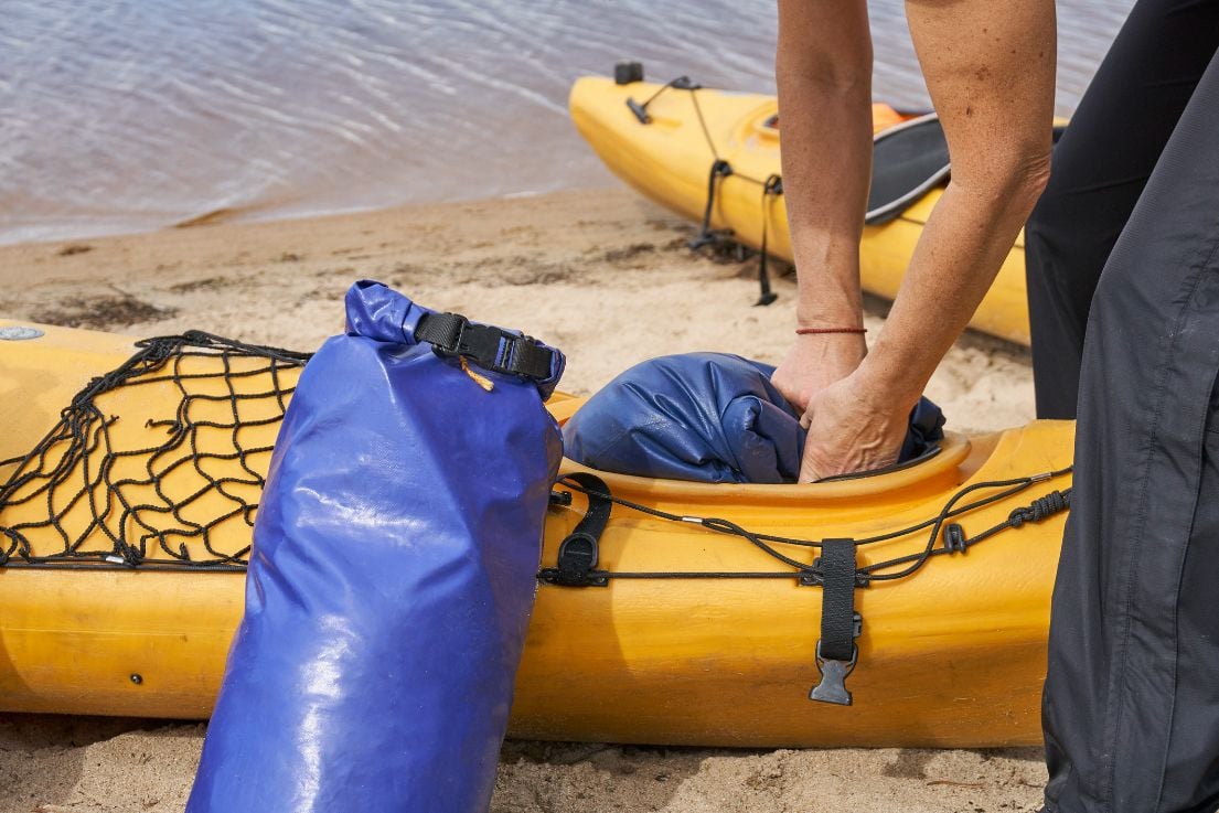 Someone squeezing a dry bag inside a kayak.