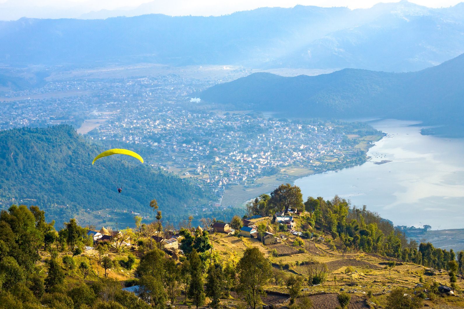 A paraglider descends onto the central hub of Pokhara and Phewa Lake, as seen from Sarangkot, Nepal. Photo: Getty