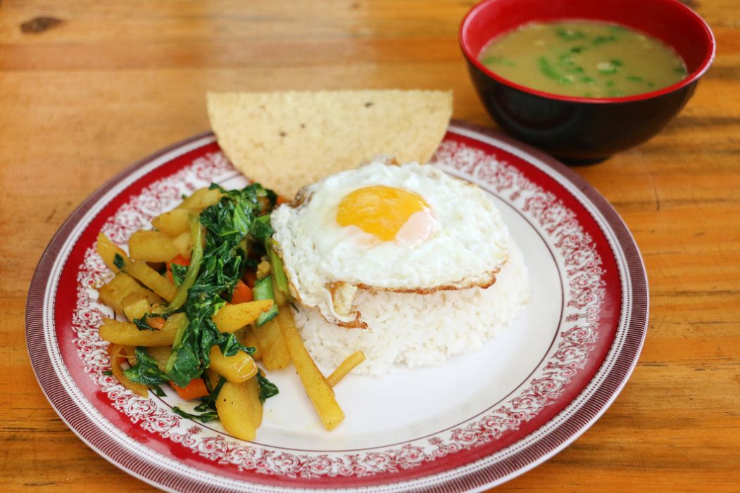 A meal in a Nepali trekking hut, including vegetables, rice and a fried egg.
