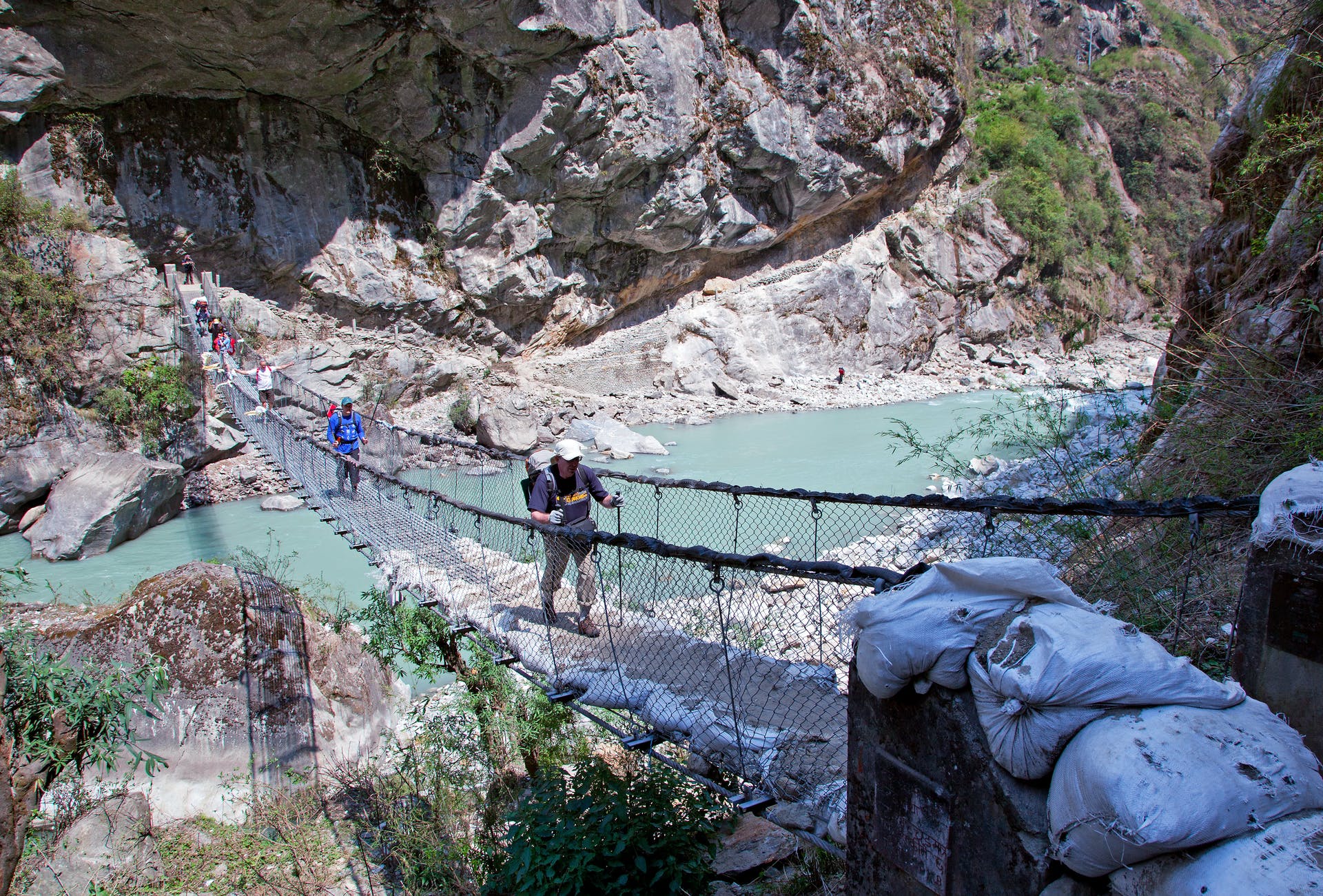 A group of hikers make their way over a suspension bridge in Nepal.