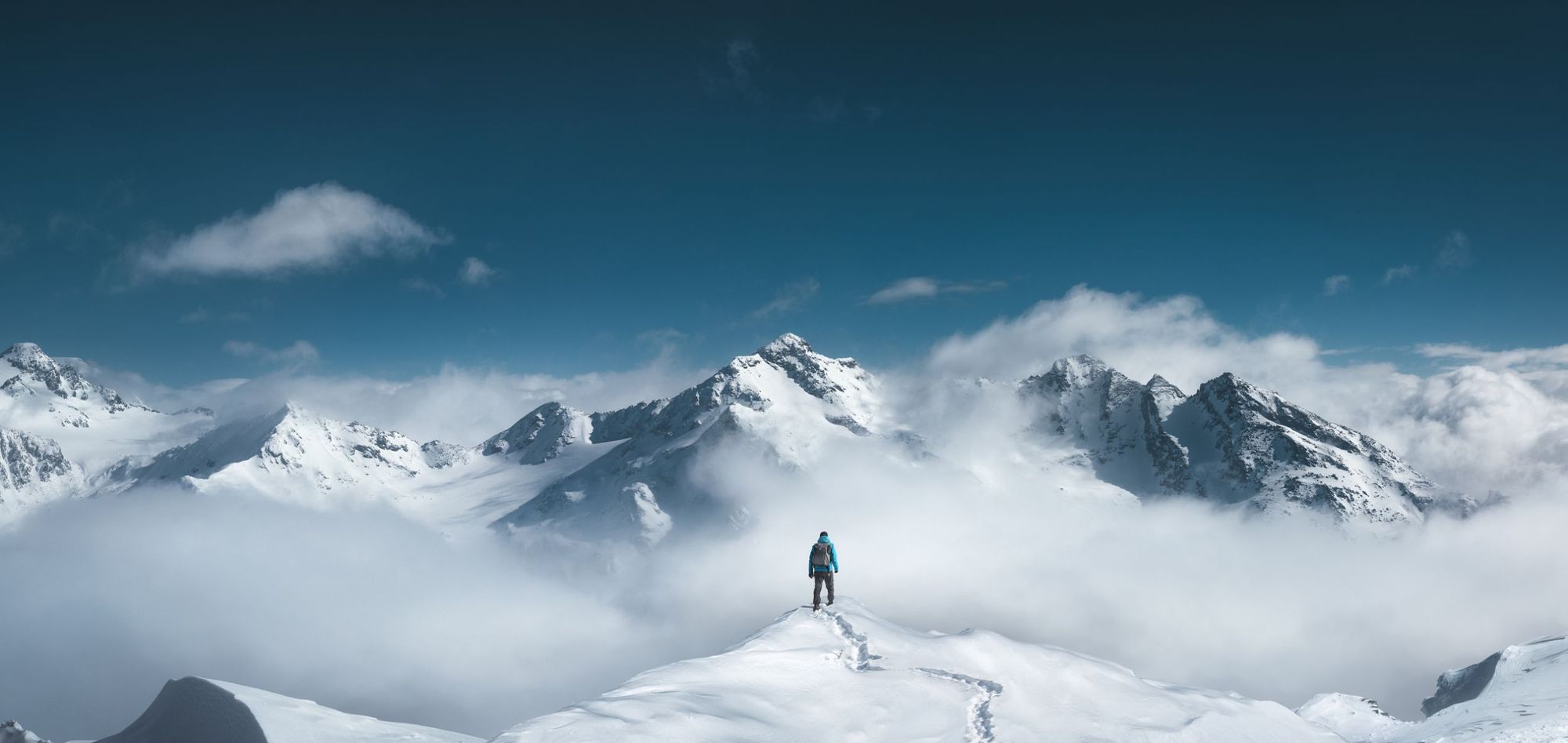 A mountaineer looks out over a snowy landscape, the kind often described in mountaineering books.