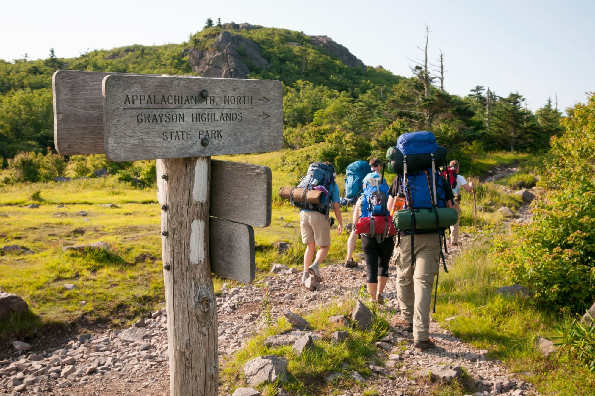 A group of hikers along the Appalachian trail - a signpost in the foreground points the way.