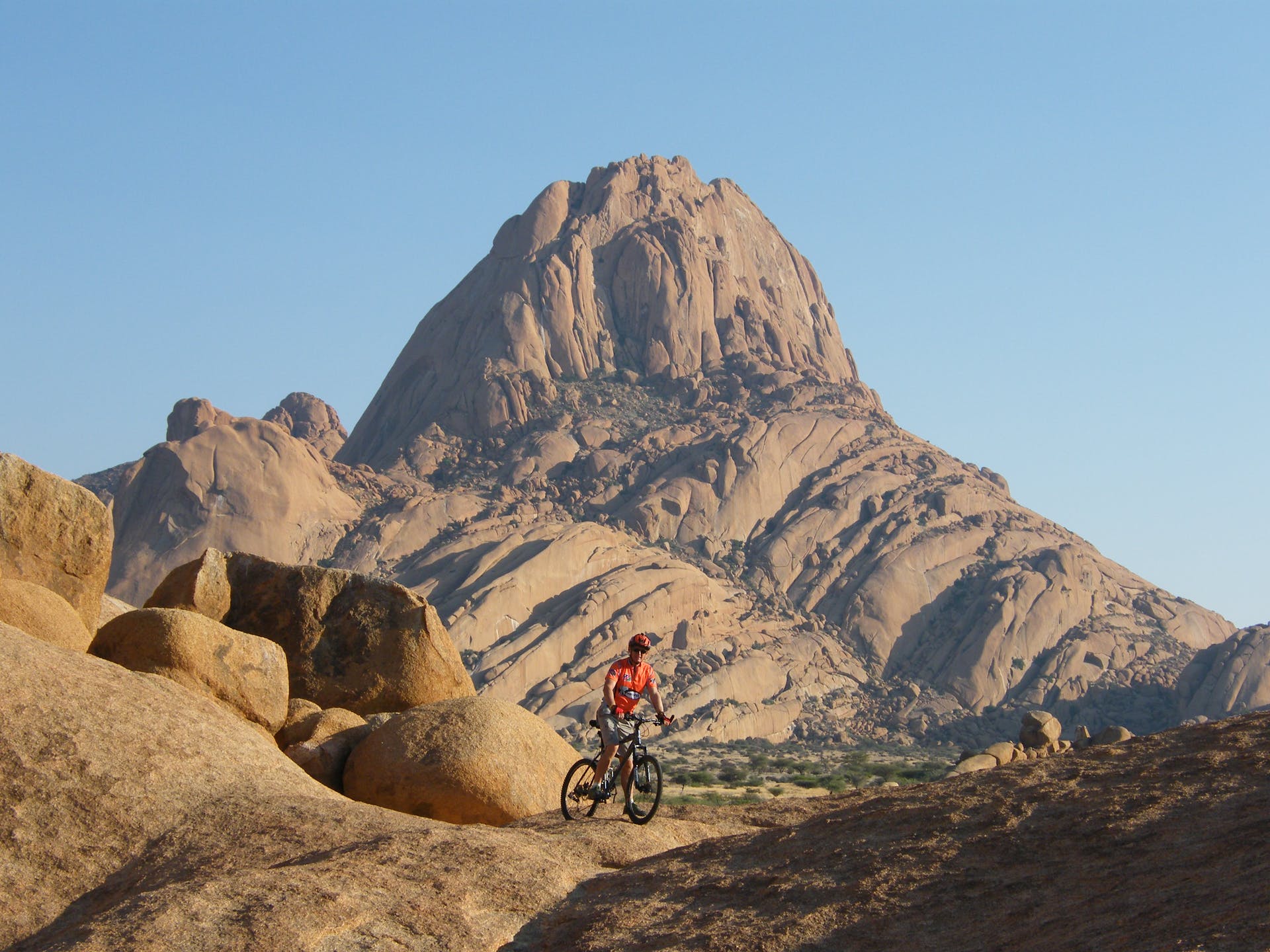 A cyclist in Namibia, with Spitzkoppe Mountain in the background.
