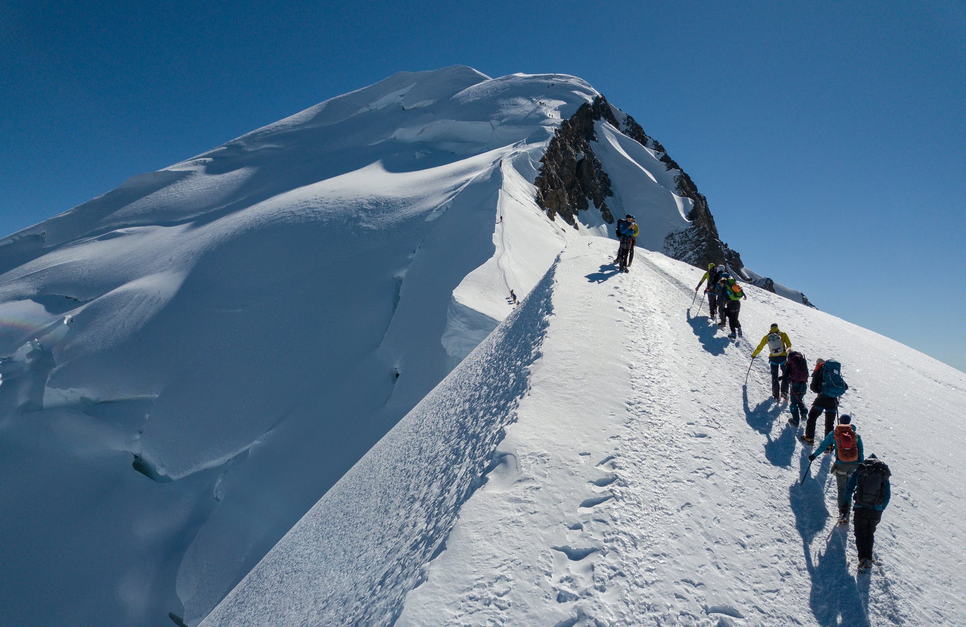 A hiking group climbing the snowy summit of Mont Blanc.