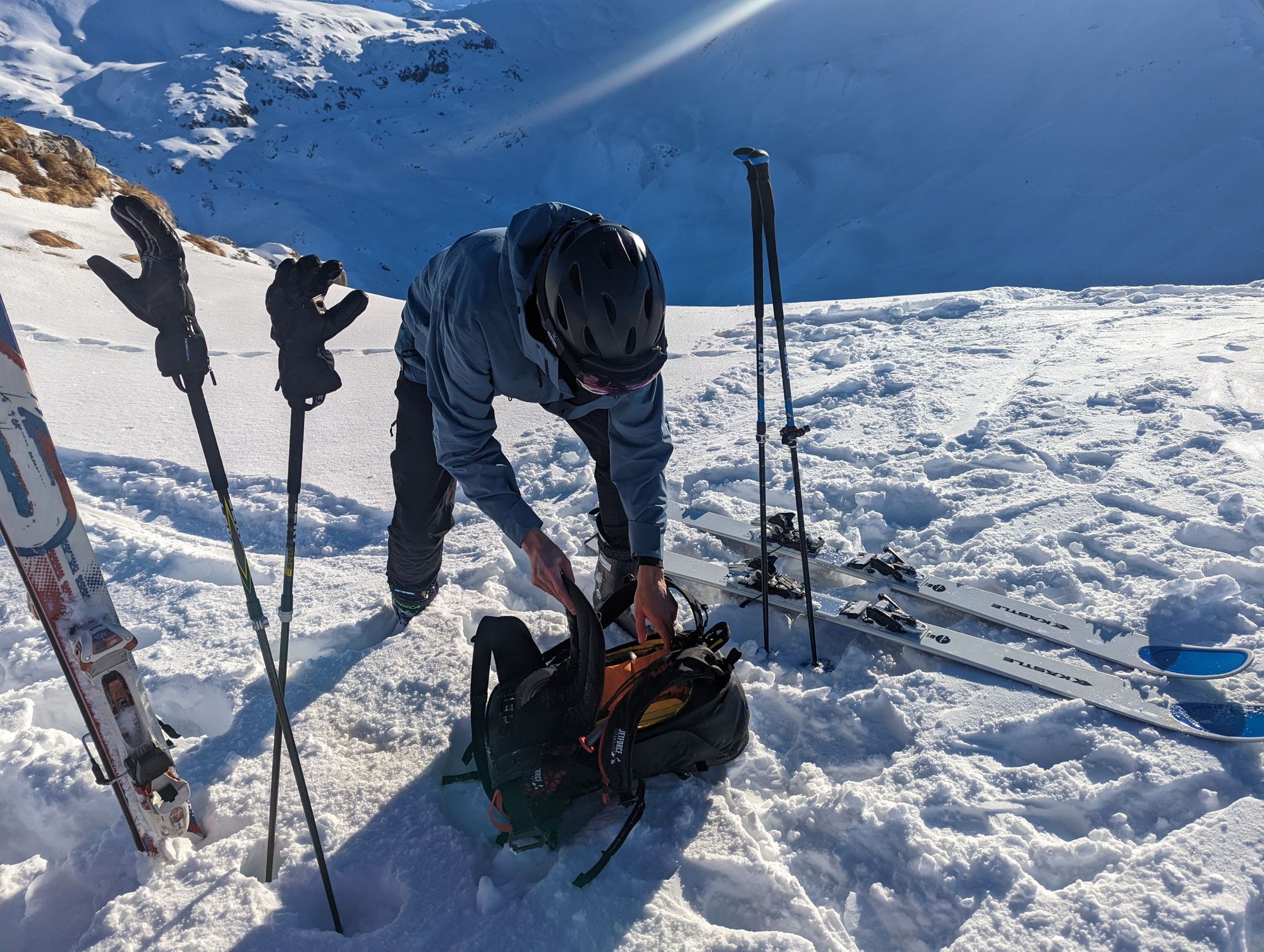 A skier gets something out of their bag.