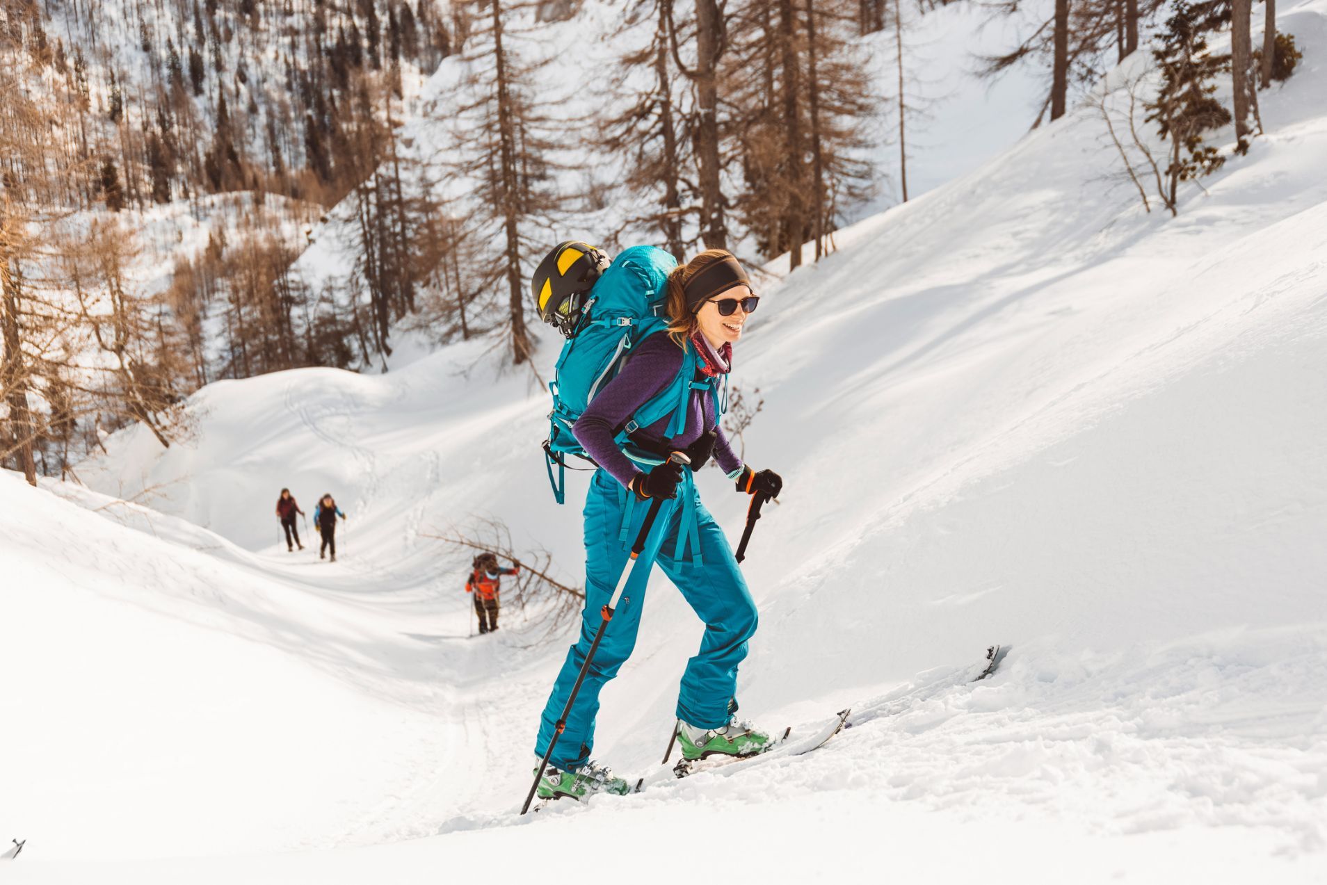 A ski tourer poses with her kit on her back - the rest of the group are behind her