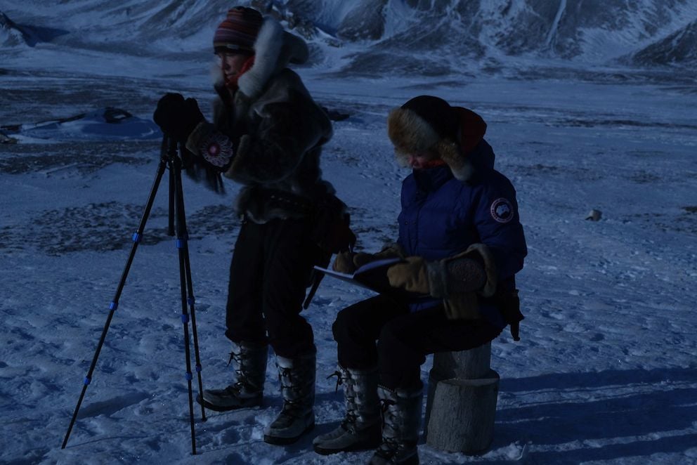 Two women photographing and observing the clouds in the Arctic.