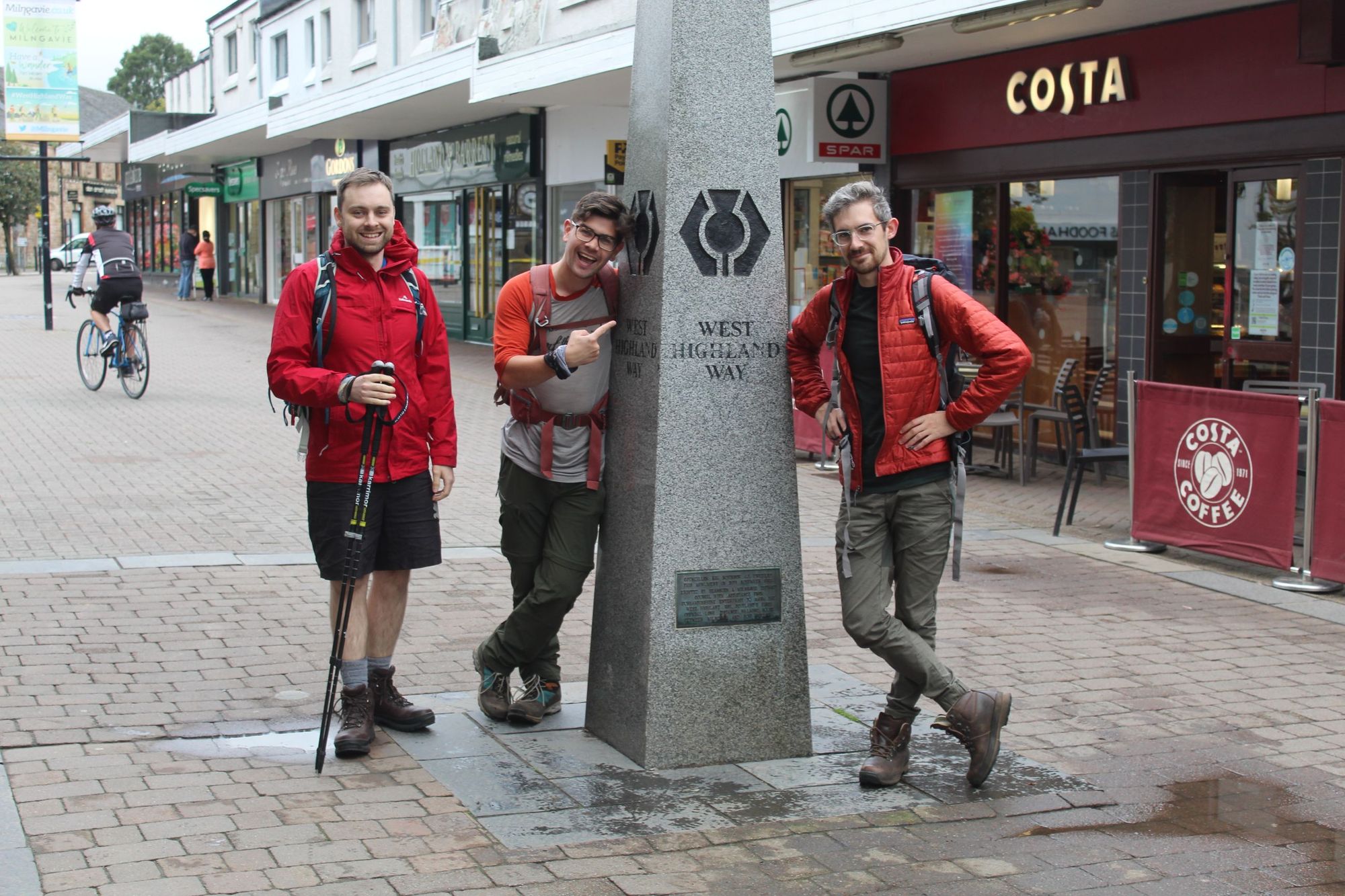 Three hikers posing by the West Highland Way start point, in Milngavie
