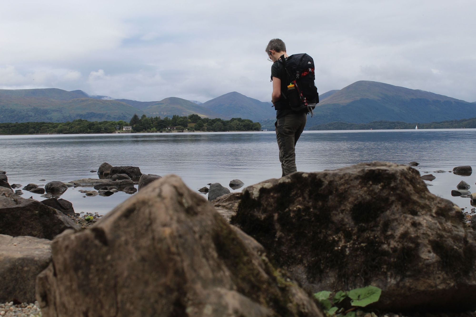 A hiker standing on the shore of Loch Lomond
