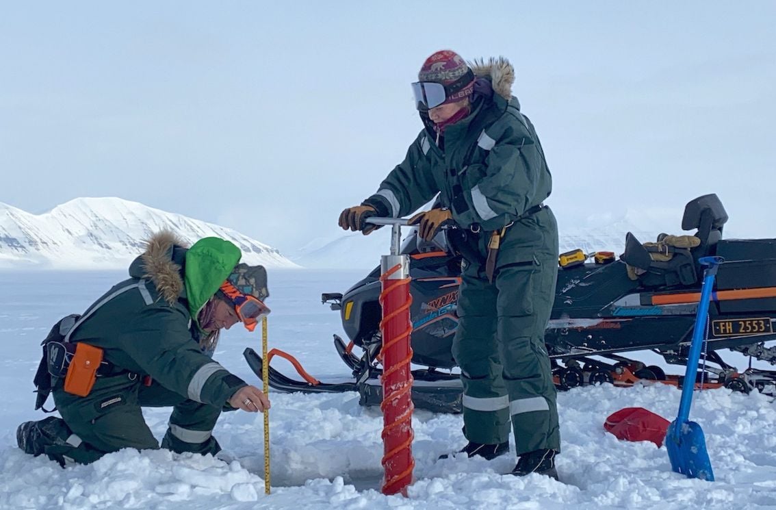 Hilde and Sunniva using a drill to extract ice core samples.