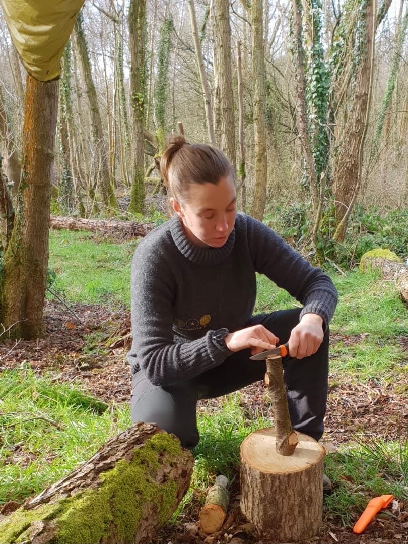 Lizzy Maskey demonstrating how to split logs using a bushcraft knife.