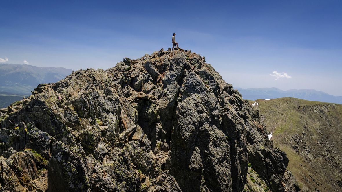 A hiker poses at the top of Pic Carlit, a mountain in the French Pyrenees