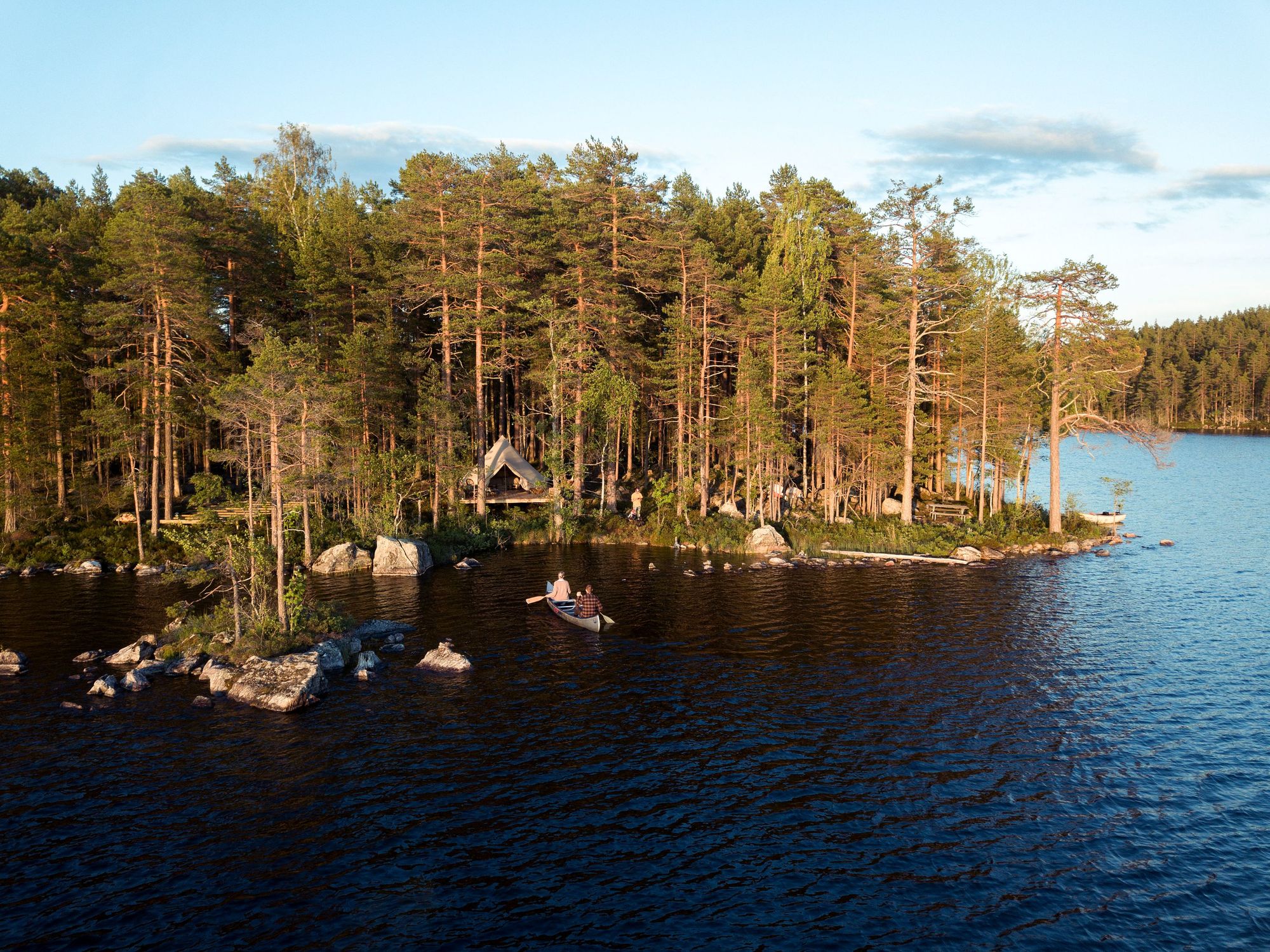 A kayaker paddling into a remote forest camp in central Sweden.