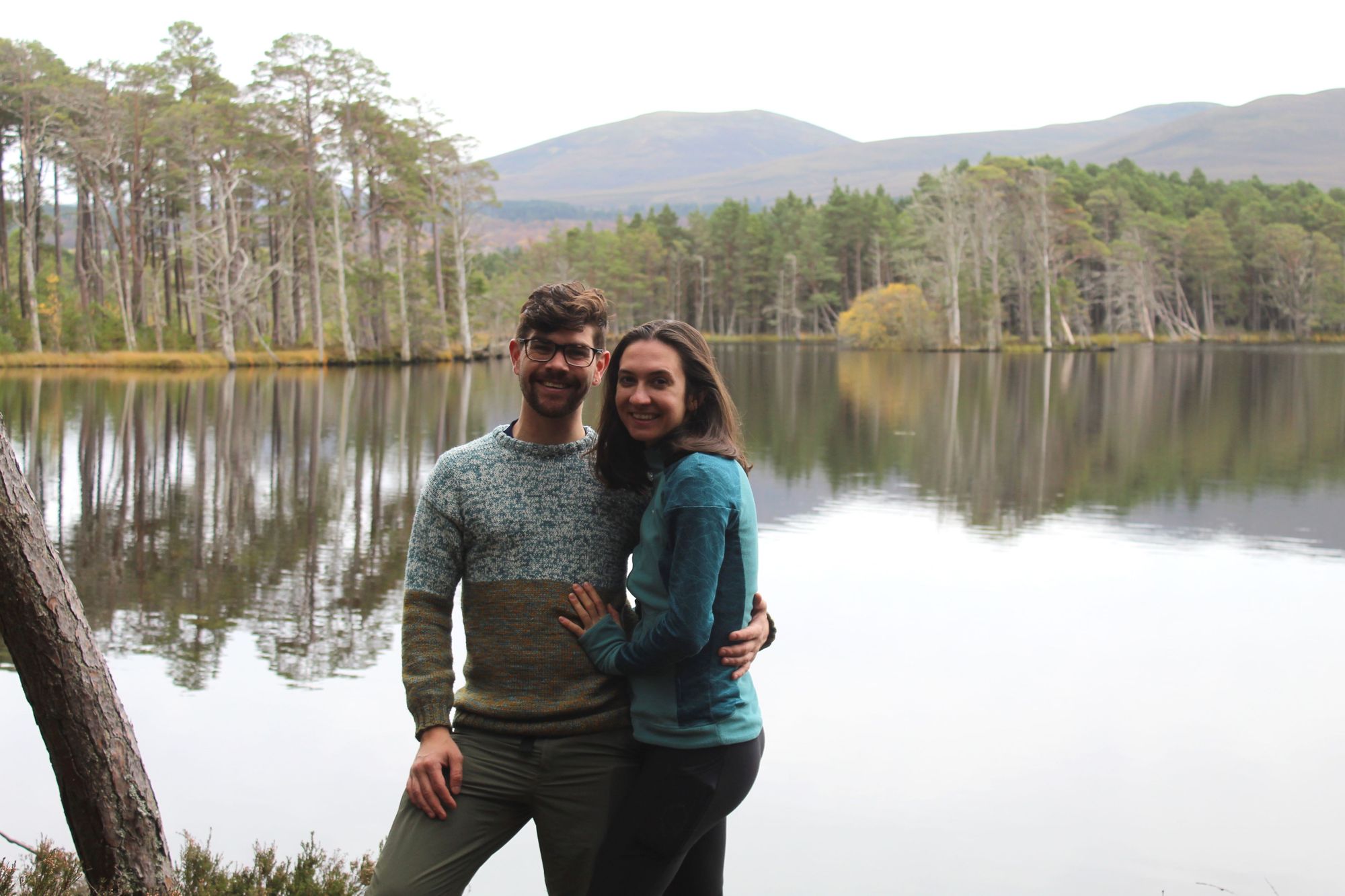 A male and female hiker pose in front of Loch Garten in the Cairngorms