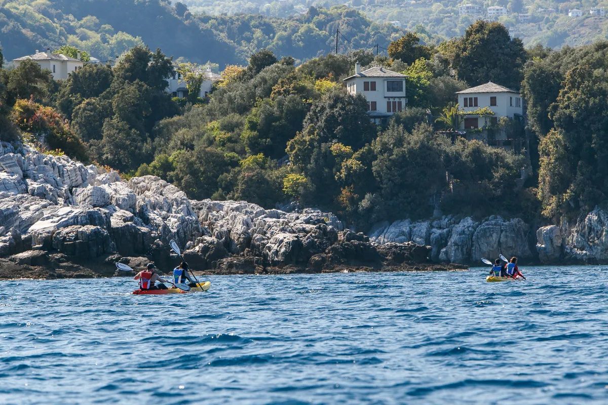 Kayakers paddling along the shoreline of the Pelion Peninsula.