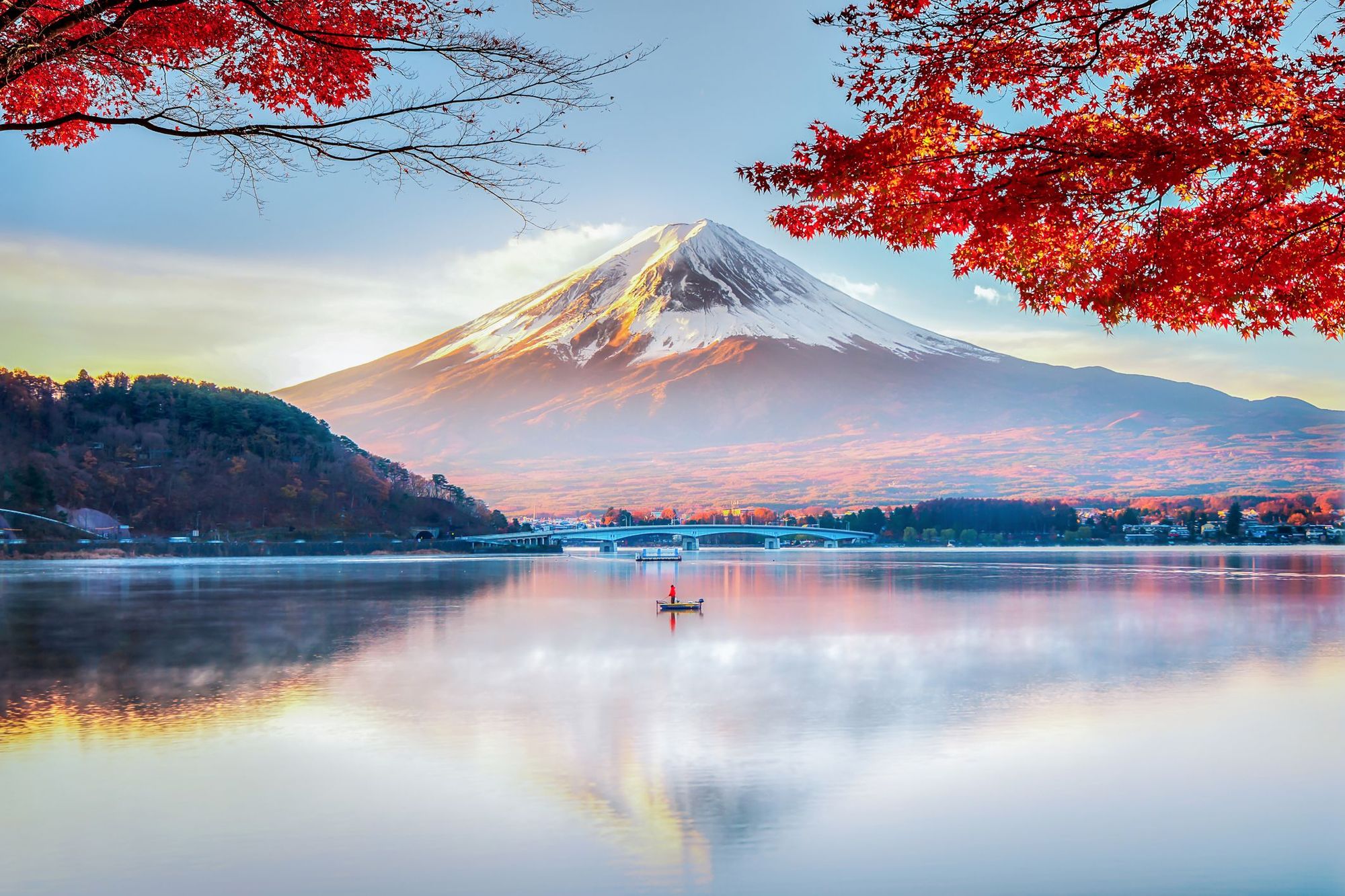 The cone-shaped summit of Mount Fuji, with a lake in the foreground.