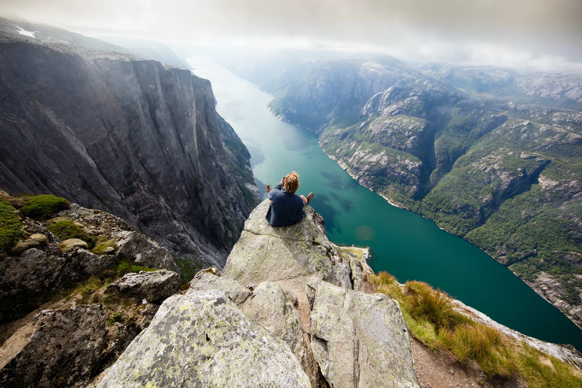 Person sat on rock up high overlooking amazing fjord views
