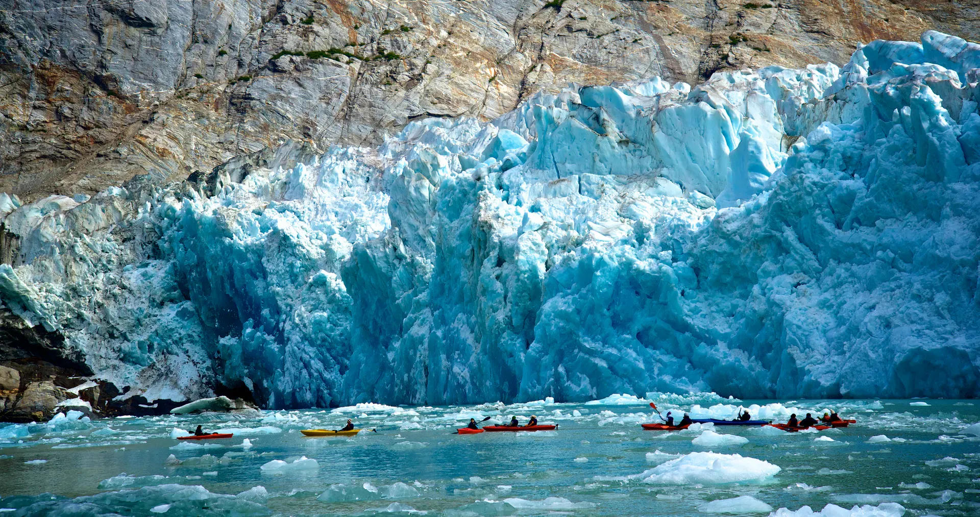 Kayakers paddling past a glacier