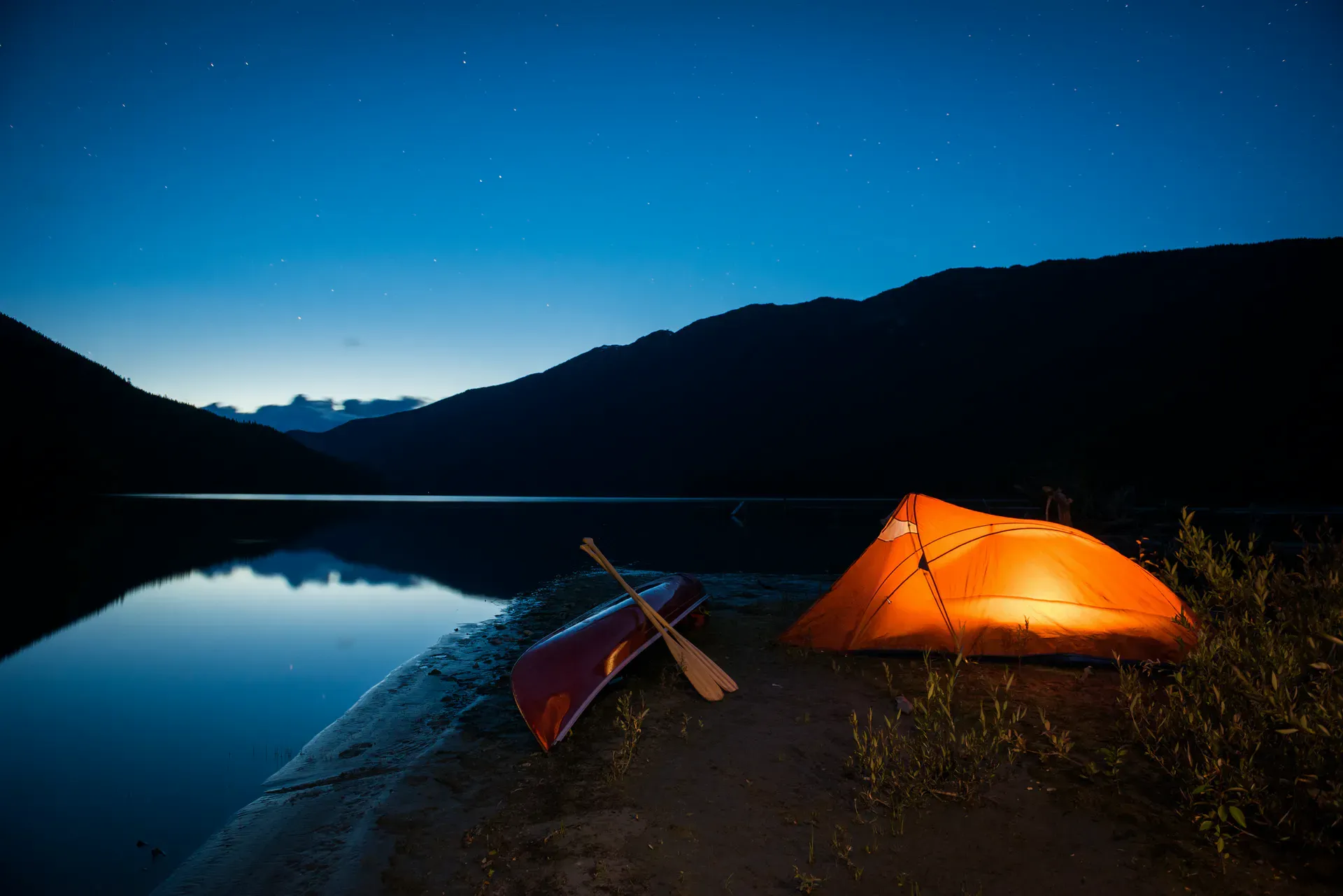 Canoe and tent by a lake at dusk
