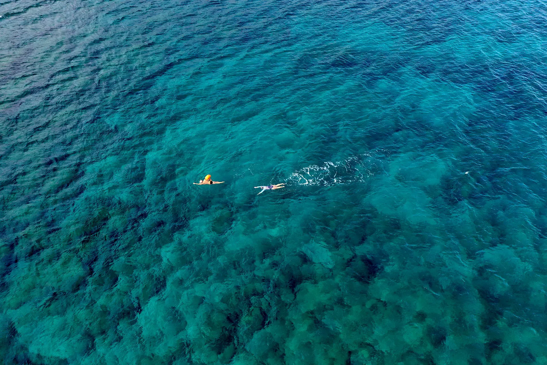 Swimmers in clear turquoise sea of Crete