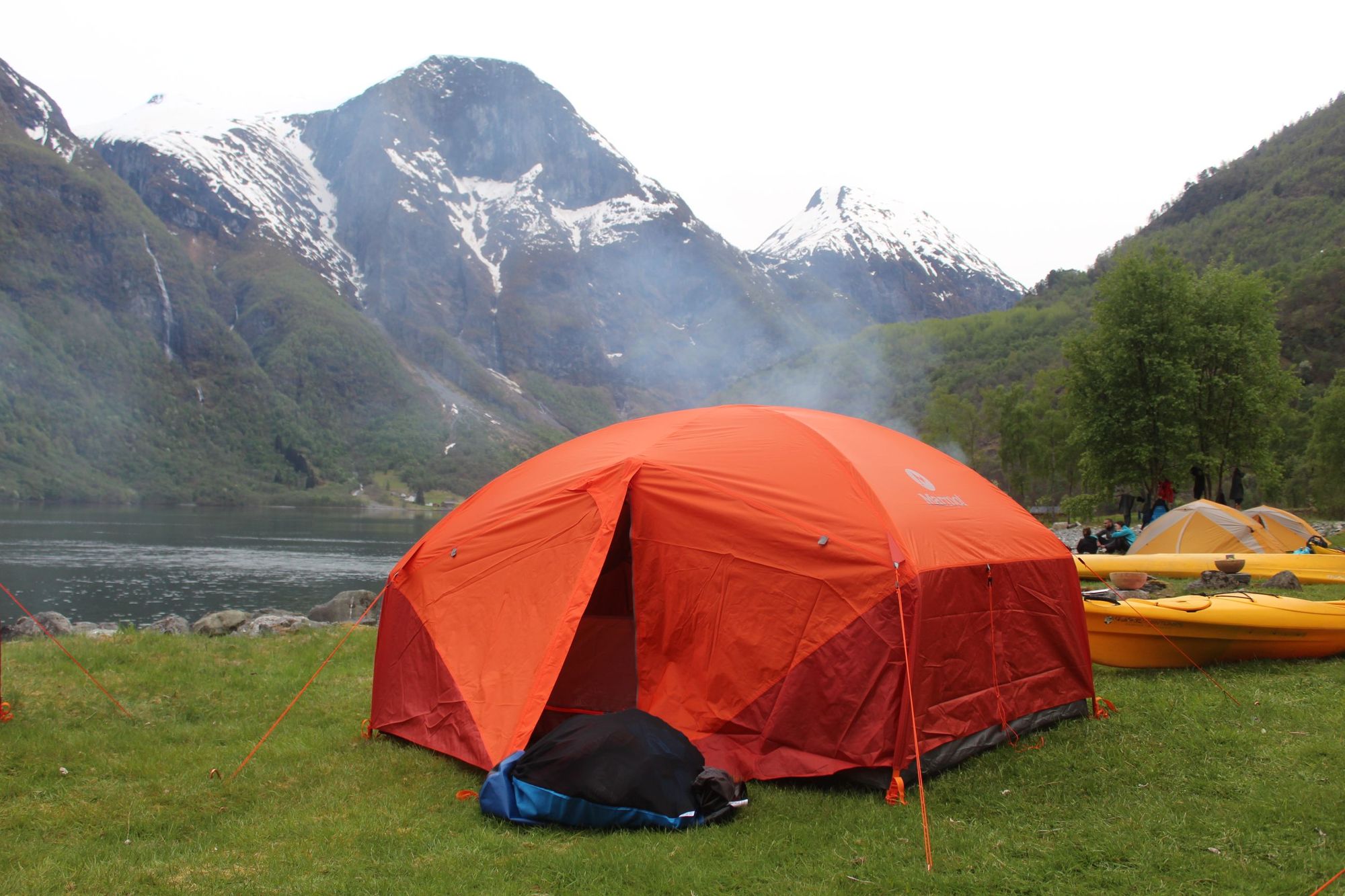 A tent set up on the egde of a fjord in Norway, with the mountains riding high in the backdrop