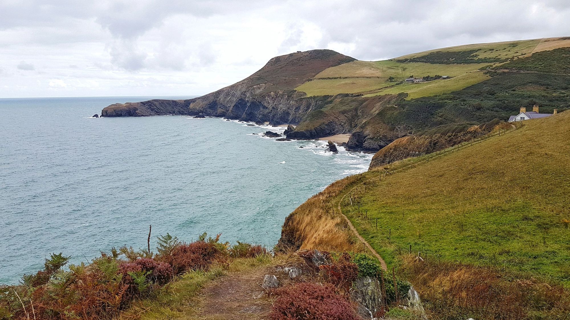 The coastline of Llangrannog, Wales, on a cloudy day.