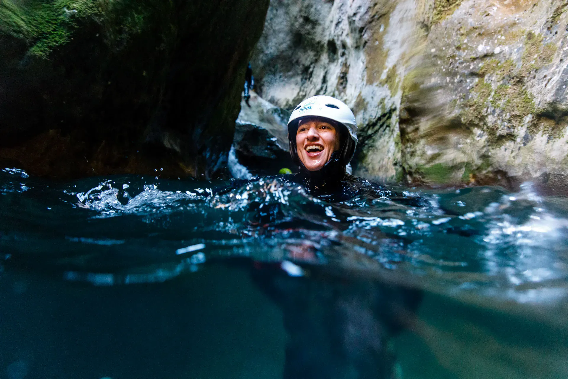 Smiling person submerged in water in a gorge