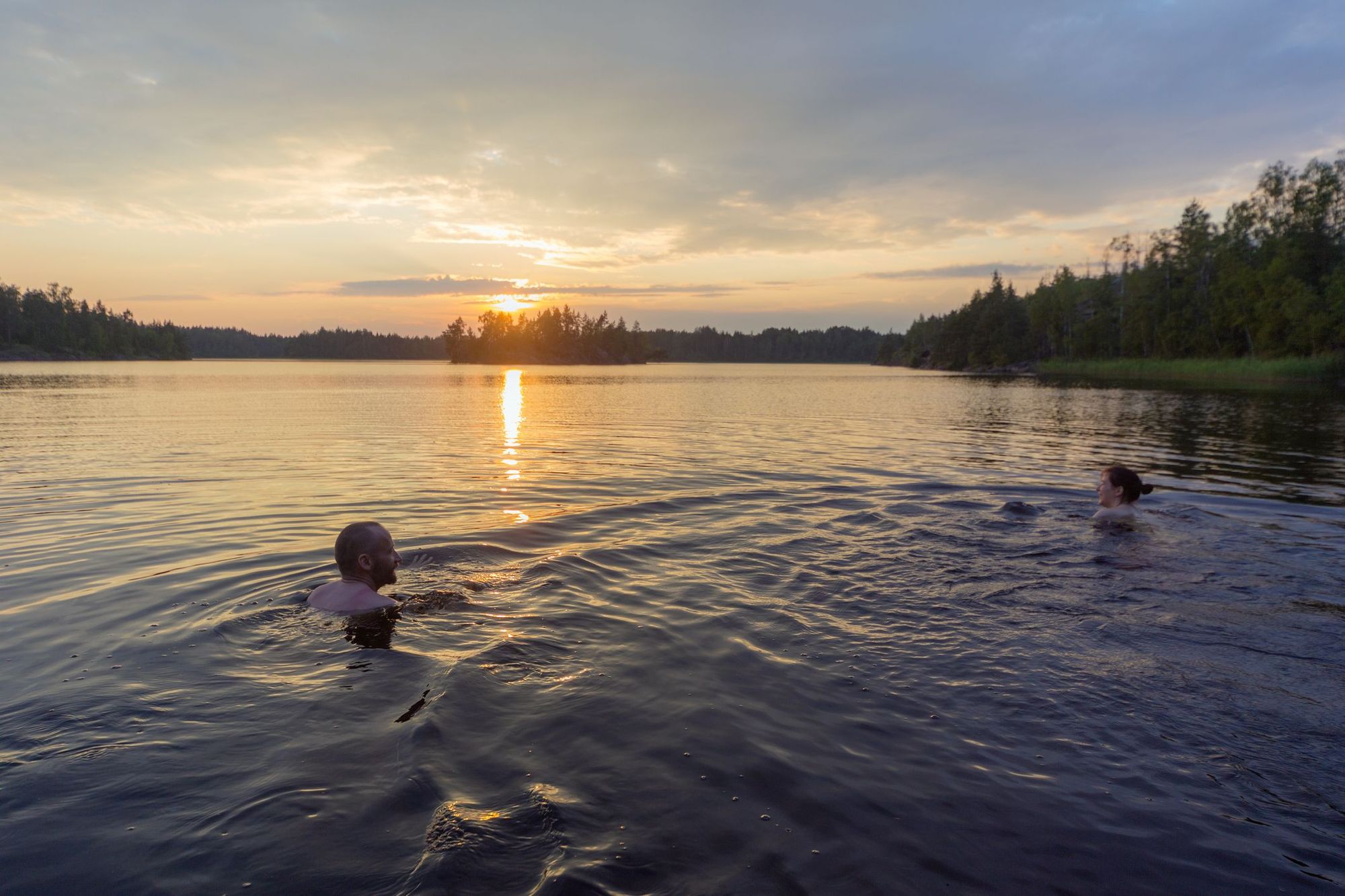 Swimmers in a lake at sunset.
